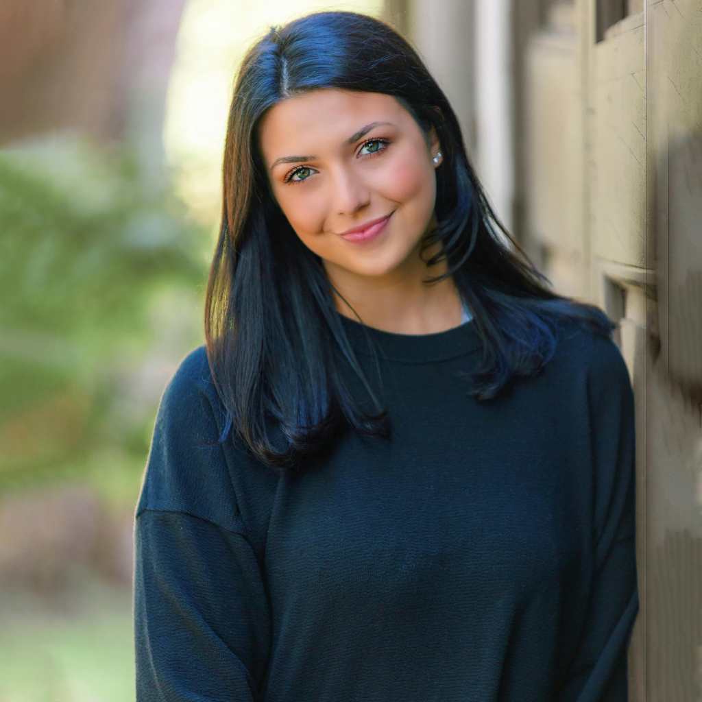 Giovane donna sorridente in un ambiente naturale, rappresentativa della bellezza e della cura di sé.